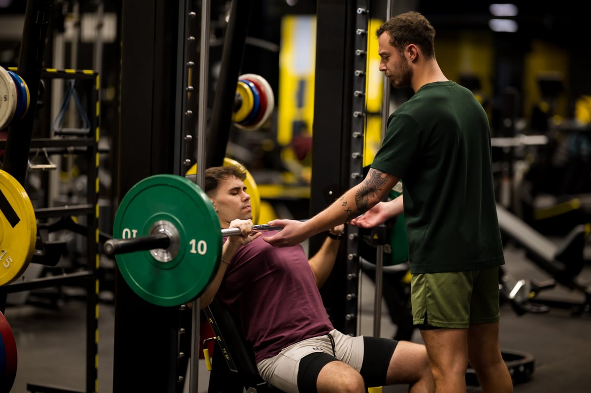 One-to-one strength coaching and spotting during a gym session